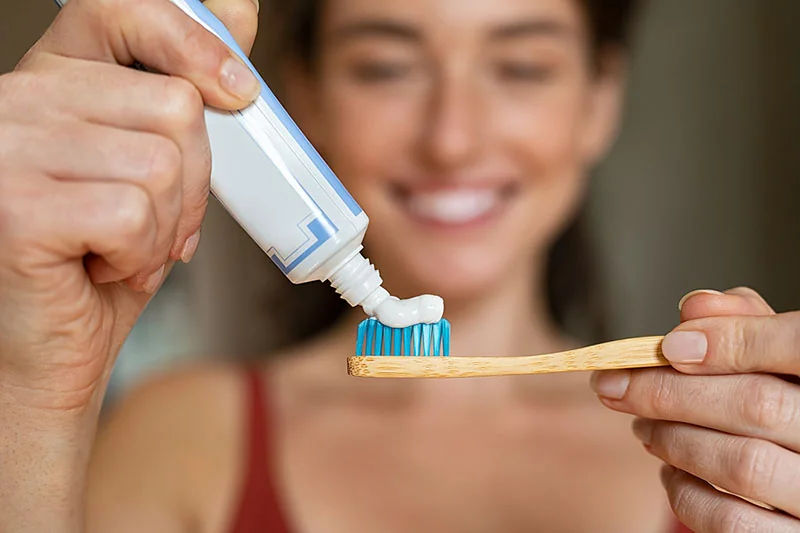 Woman using toothpaste on toothbrush