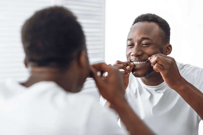 Smiling man using dental floss